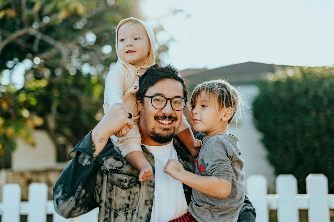 Man in white shirt carrying girl in gray shirt